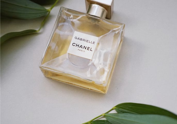 Bottle of Chanel parfume with green leaves on top and bottom