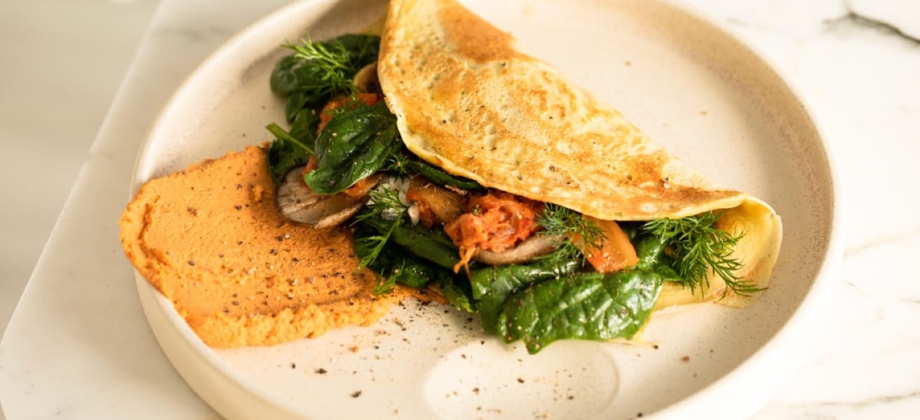 Photo of an wrapped omelette with chicken and salad on a plate